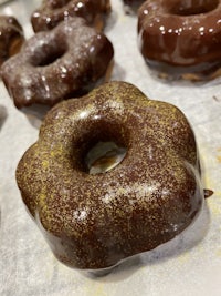 a bunch of chocolate glazed donuts on a baking sheet